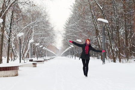 Beautiful happy girl in black walks outdoor at winter day in parkの写真素材