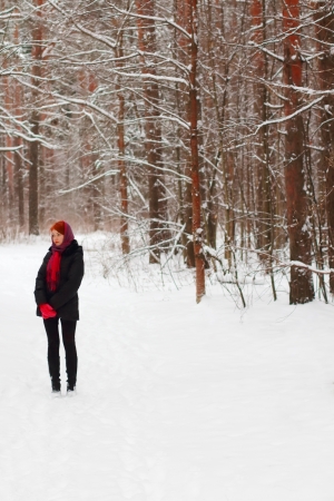 Pretty young girl stands and looks away at winter day in forestの写真素材