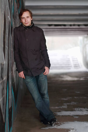 Young man stands in small tunnel at winter evening and looks at cameraの写真素材