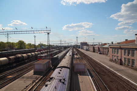 long passenger and freight trains at railway station in sunny dayの写真素材