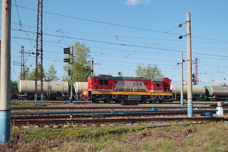 Freight trains and small train at railway station with many electric wires at summer の写真素材