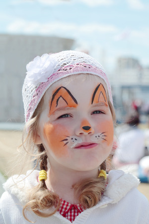 Little beautiful girl with face painting of orange fox at sunny dayの写真素材