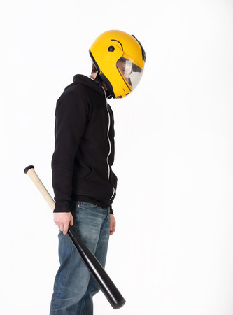 Thin man in yellow helmet and black jacket with bat in his handの写真素材
