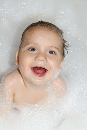 Happy kid in white soapsuds looking upの写真素材