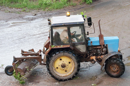 Blue old and rusty tractor running after rain storms and summerの写真素材