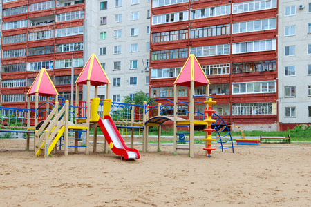 Colorful playground in sand next to high-rise residential buildingの写真素材