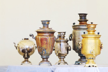 Five Russian samovars of different shapes and sizes are on table with blue tableclothの写真素材