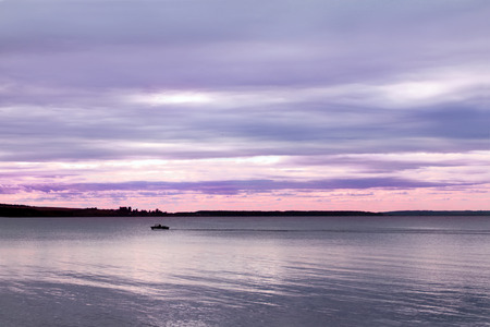 Lonely motor boat floats on Kama big River in summer eveningの写真素材