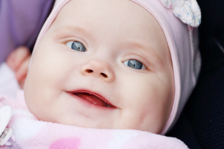 Closeup of beautiful cute little girl is in carriage and smiling
