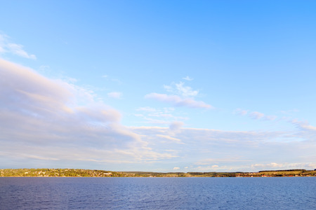 View of river and shore with settlements in distance on hot sunny dayの写真素材