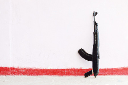 Wooden black toy rifle leaning against pink wallの写真素材
