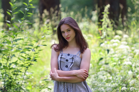 Close-up of beautiful girl in dress and long hair with view of forest in background with shallow depth of fieldの写真素材