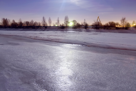 Frozen river covered with ice reflects light from moon at nightの写真素材