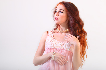 Closeup portrait of beautiful young dreaming girl with red long hair in studioの写真素材