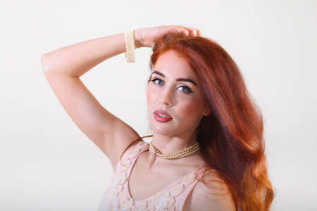 Portrait beautiful young smiling girl with red long hair with hand on headの写真素材