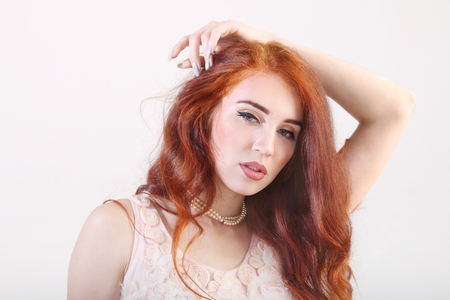 Closeup portrait beautiful young smiling girl with hand on headの写真素材