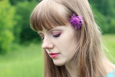 Close up portrait of beautiful woman with closed eyes and wildflower in hairの写真素材