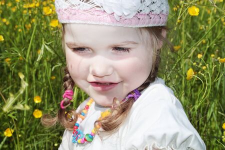 Close up view of little girl is among yellow flowers at meadow at summer dayの写真素材