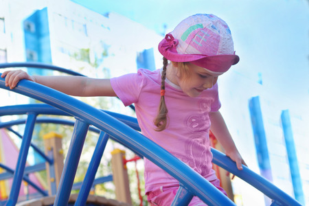 Pretty little girl plays on wooden children playground at summer dayの写真素材