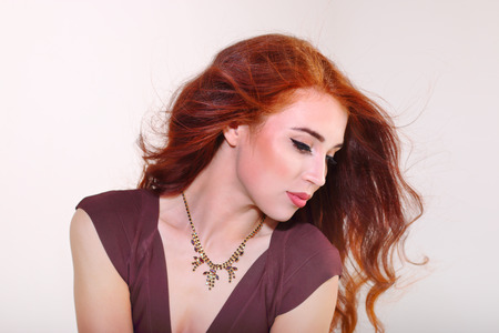 Closeup beautiful young girl with red hair posing in brown dressの写真素材