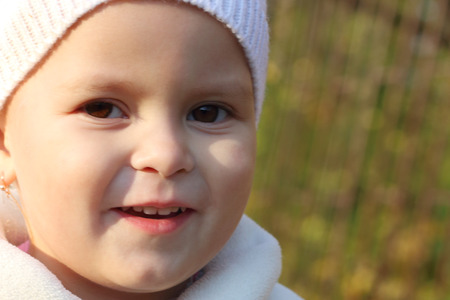 Close up portrait of little girl in hat near yellow trees and fence at autumn. Shallow dofの写真素材