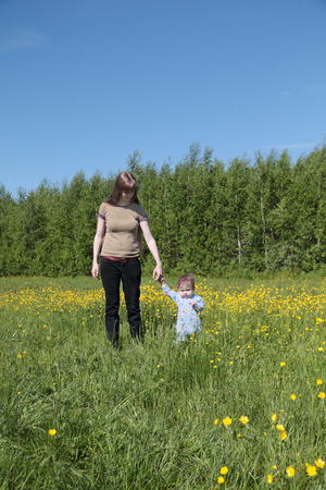 Young mother go with little son near green forest at summer dayの写真素材