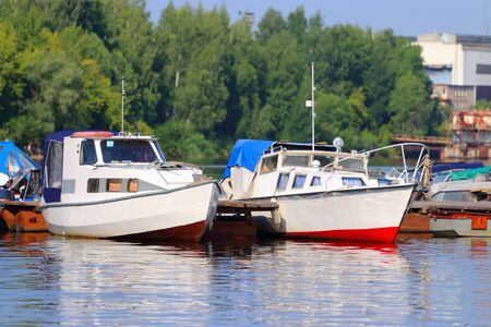 Small modern motorboats at pier on river at summer sunny dayの写真素材