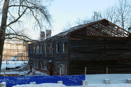 Two-storey abandoned wooden house made of logs on winter sunny dayの写真素材