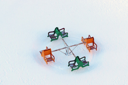 Top view of carousel at children playground covered by snow at winter day