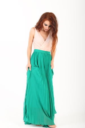 Standing barefoot beautiful young girl posing with red hair and green skirtの写真素材