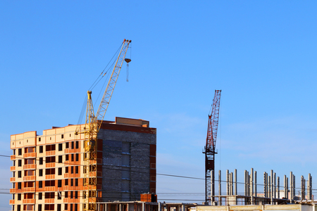 Part of tall cranes and building under construction at sunny winter dayの写真素材