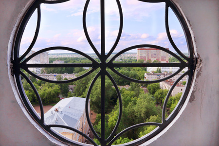 View through round window of residential buildings among treesの写真素材
