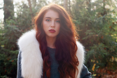 Pretty girl with white fur poses in forest at warm sunny dayの写真素材