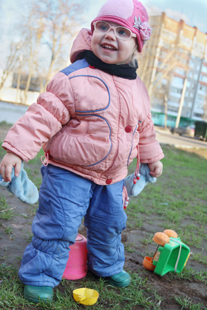 Happy little girl in fake glasses plays with plastic toys outdoorの写真素材