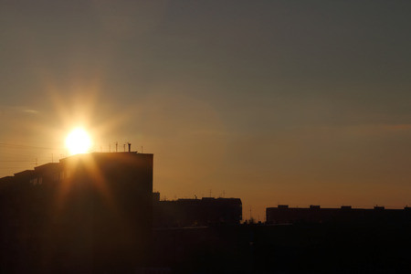 Beautiful sun during sunset over roofs of residential buildings in townの写真素材