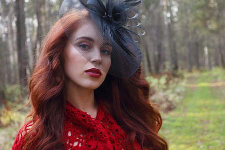 Pretty girl in black hat poses in autumn forest at warm sunny dayの写真素材