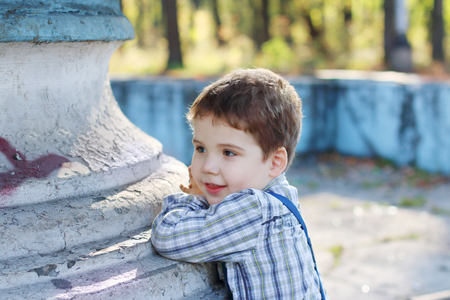 Handsome little boy with bow tie stands near old fountain in park, shallow dofの写真素材