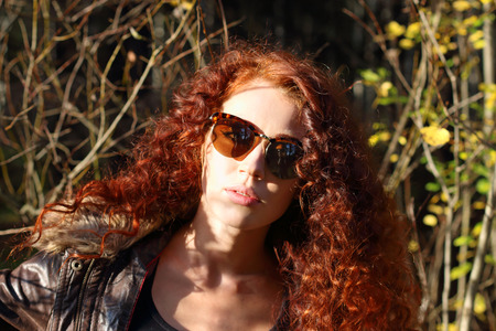Pretty woman in sunglasses at sunny day in autumn forestの写真素材