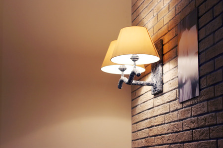 Sconce with yellow lamp shade on brick wall with pictures indoorの写真素材