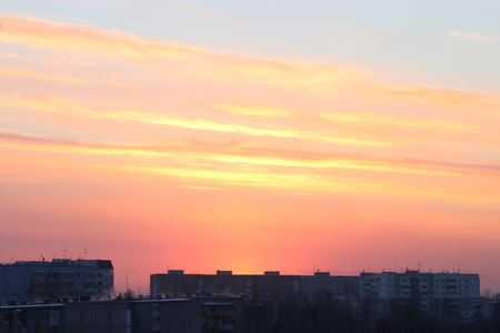 Beautiful bright sunset over roofs of residential buildings in townの写真素材