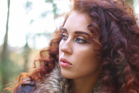 Girl with curly hair in leather jacket in sunny autumn forest, shallow dof, close upの写真素材