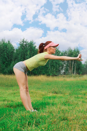 Girl with a beautiful slender, athletic figure doing exercises outdoors.の写真素材