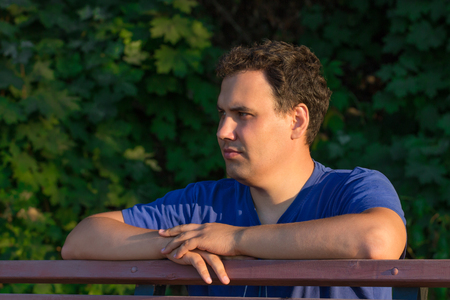 A young man walks in the Park, admiring the vivid greens and basking under the rays of the sunの写真素材