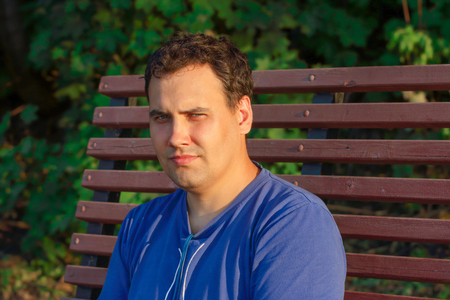The young man warm spring day sitting on the bench under the bright rays of the sunの写真素材
