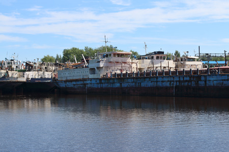 Big rusty cargo ships are in bay on river at summer sunny dayの写真素材
