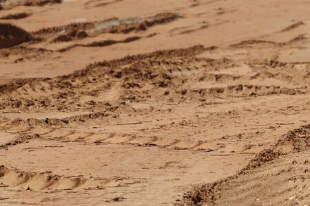 Yellow sand with many tractor tracks on construction site at sunny day