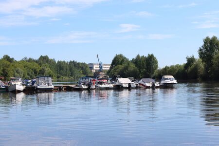 Many small modern motorboats at pier on river at summer sunny dayの写真素材