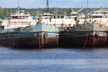River bay with rusty cargo ships on summer day, ships bows with anchorsの写真素材