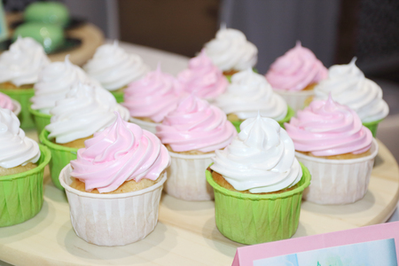 Sweet white and pink cupcakes are on table during celebrationの写真素材