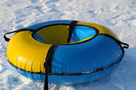 Yellow and blue snowtube is on white snow at winter sunny dayの写真素材